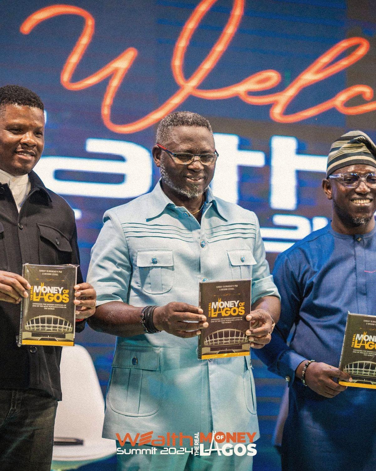 The co-founders holding copies of The Real Money of Lagos on stage